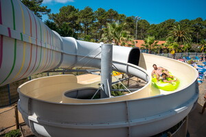 Un père et son enfant dévale le toboggan sur une bouée du parc aquatique du camping 5 étoiles Le Vieux Port dans les Landes