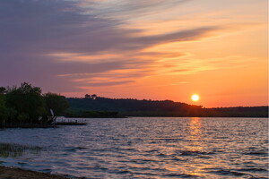 Coucher de soleil spectaculaire sur le lac de Léon, avec des reflets colorés sur l'eau et un ciel vibrant aux nuances d'orange, rose et violet.