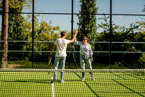 Joueurs au terrain de padel du camping des Landes qui se tapent les mains en signe de convivialité lors de leurs vacances en bord de mer dans une location tout équipée avec infrastructures de qualité