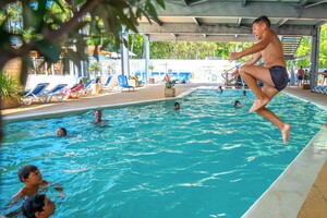 Camping avec piscine couverte et chauffée dans les Landes (3) des enfants s'amusent avec une bombe et élan pour sauter dans le bassin du parc aquatique