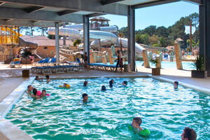 Camping avec piscine couverte et chauffée dans les Landes (6) vue sur les toboggans aquatiques du parc à thème avec enfants en bouée et leurs parents