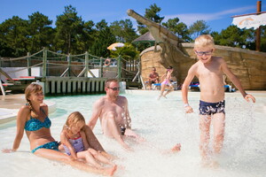 Famille se relaxant avec parents et enfants dans la pataugeoire chauffée du parc aquatique du camping 5 étoiles en bord de mer dans les Landes