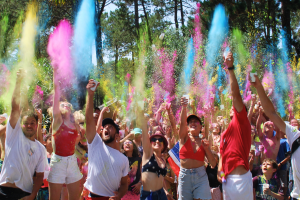 Groupe de participants en tenue colorĂ©e sautants lors d'une course Color Run, avec des poudres de couleurs vives en suspension dans l'air, sous un ciel ensoleillĂ©, cĂ©lĂ©brant la joie et la fĂȘte