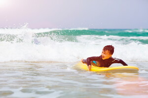 Enfant prenant un cours de surf avec l'école de surf du camping 5 étoiles Le Vieux Port à Messanges dans les Landes