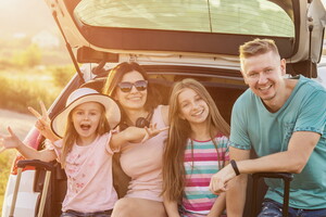 Une famille chargée de bagages dans une voiture garée devant un camping, illustrant le processus d'arrivée au camping en voiture